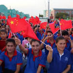 Bir ayakkabı fabrikasında Çin bayrakları sallayan Uygur işçiler.