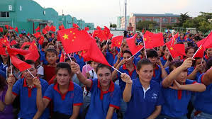 Bir ayakkabı fabrikasında Çin bayrakları sallayan Uygur işçiler.